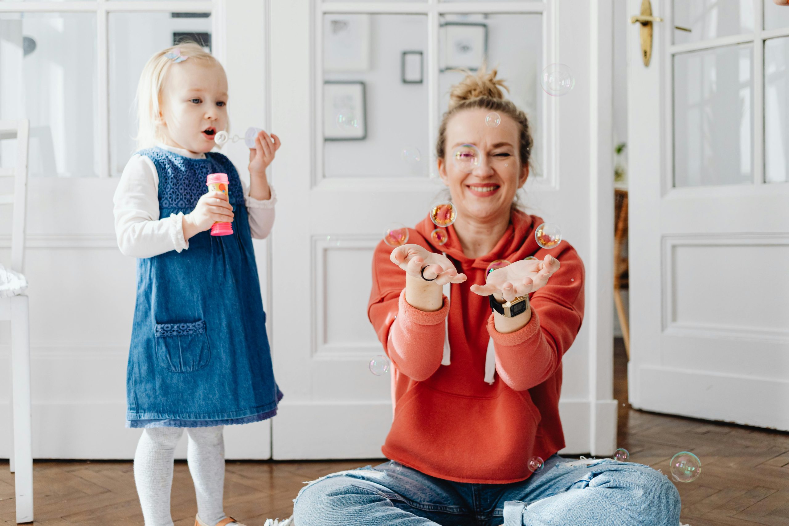 אמא וילדה משחקות ביחד בהנאה בבועות סבון.